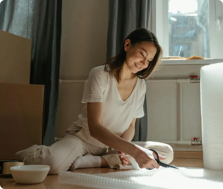 Mujer sonriente preparando cajas para mudarse-Propiedad segura